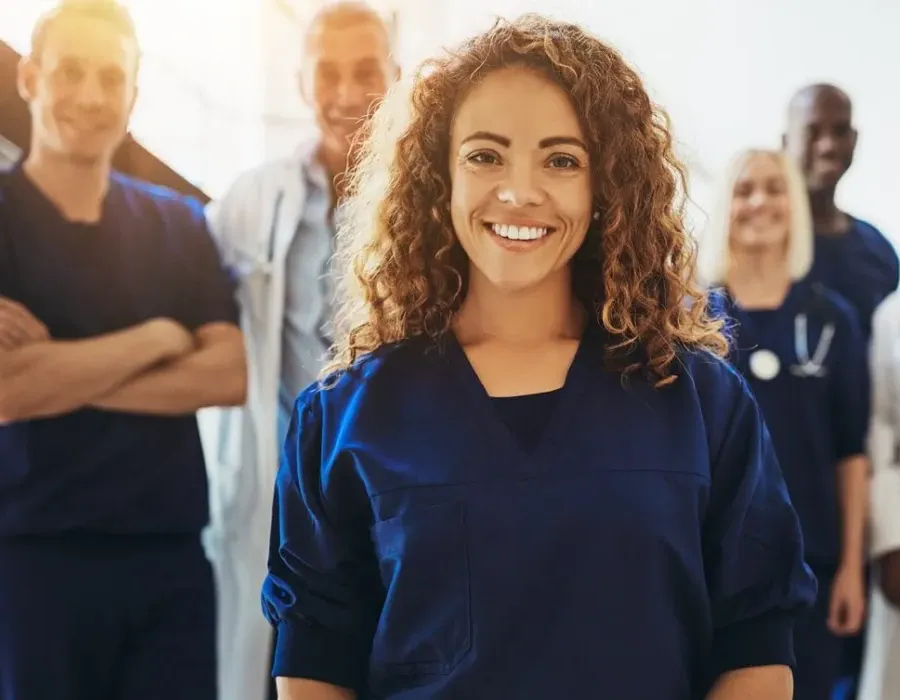 Nursing student who was formerly a medical assistant smiling in group photo with healthcare staff